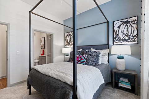 A bedroom with a four poster bed and a grey carpet.