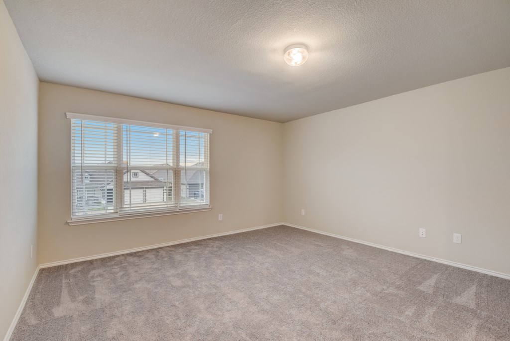 an empty living room with a window and carpet