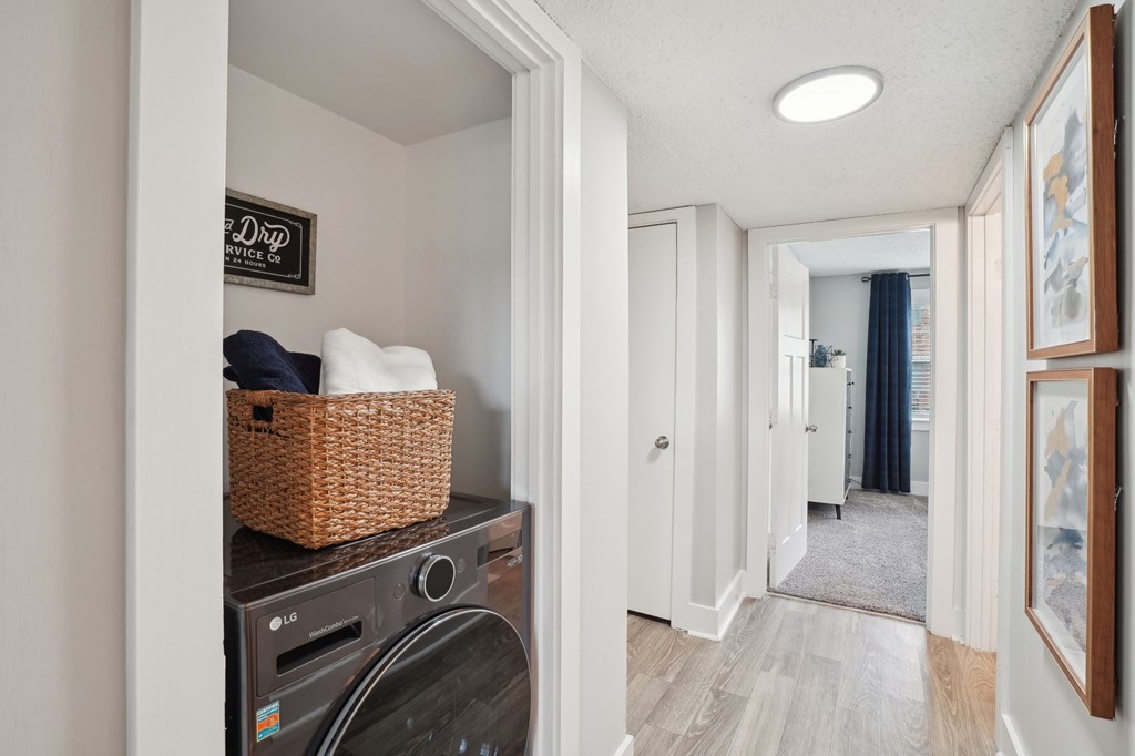 Laundry area with LG WashCombo, woven basket of towels, and hallway view.