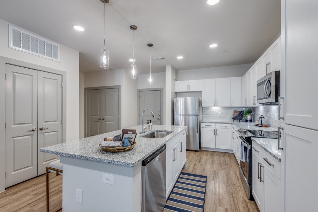 a large kitchen with white cabinets and stainless steel appliances