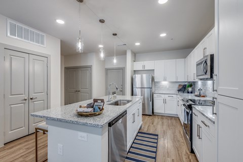 an open kitchen with white cabinets and stainless steel appliances