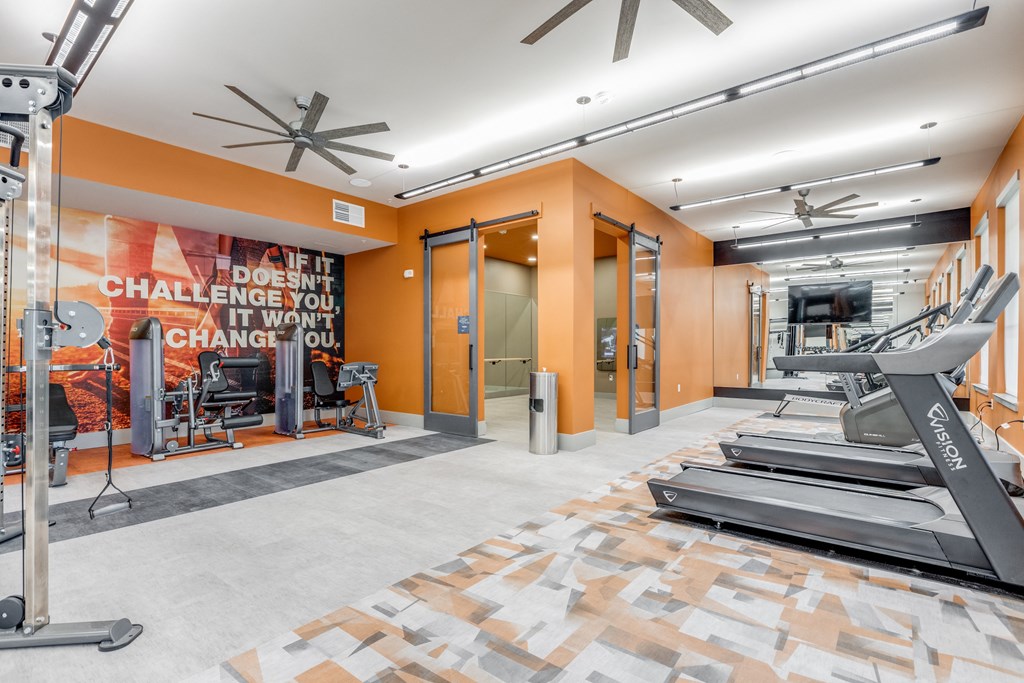 a gym with cardio equipment and a wall with a quote on it