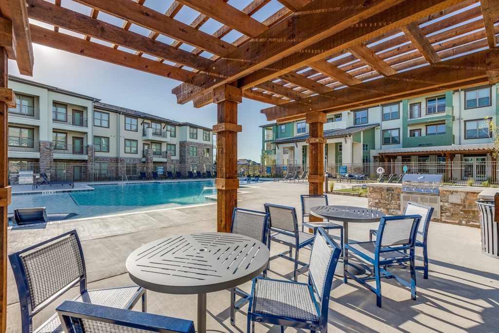 a patio with tables and chairs next to a swimming pool