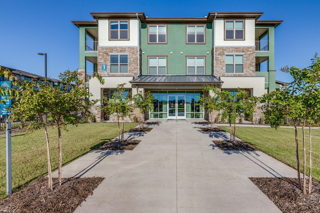 a large building with a sidewalk and trees in front of it