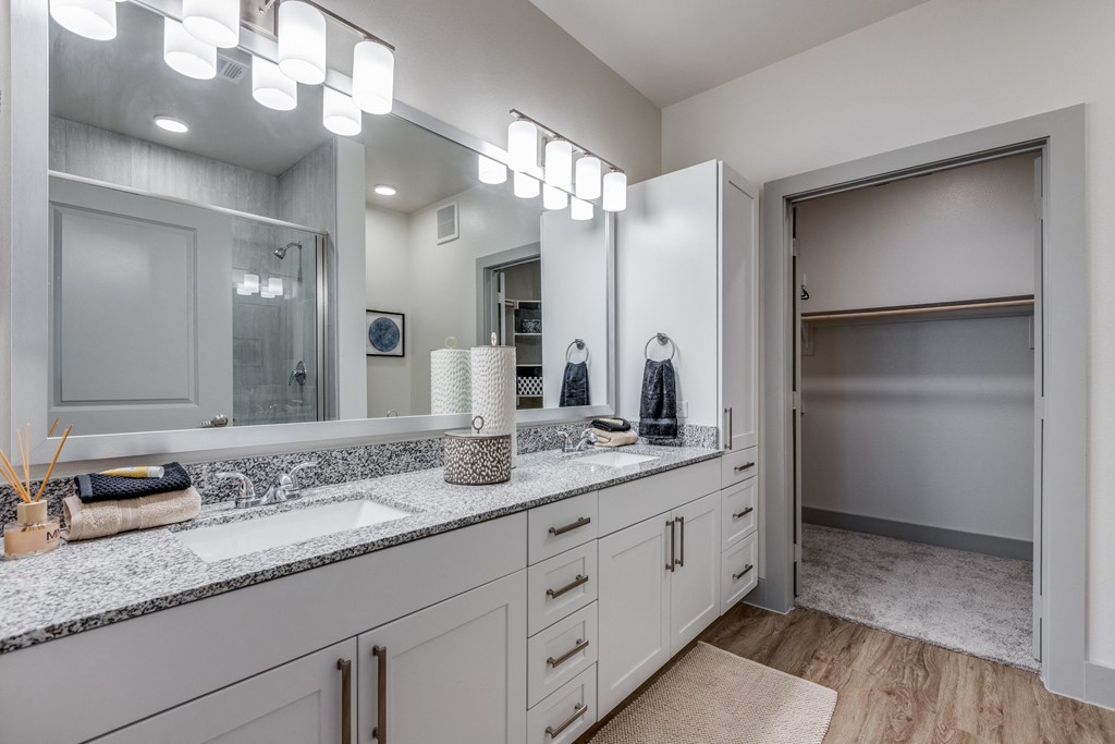 a bathroom with white cabinets and granite counter tops and a large mirror