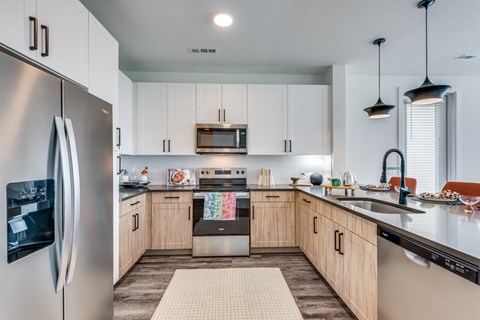 A modern kitchen with a refrigerator on the left and a stove top oven in the middle.