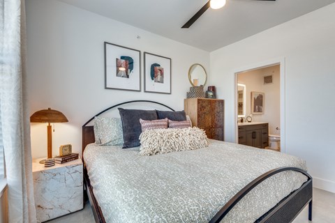 A bedroom with a large bed and a lamp on a side table.