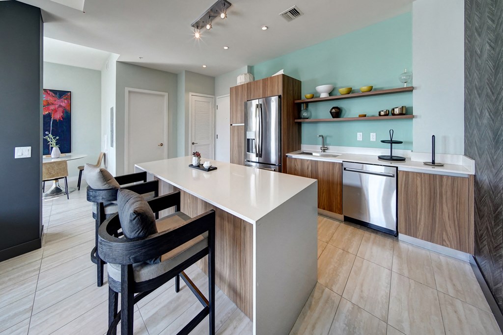 a kitchen with an island and a dining room with chairs