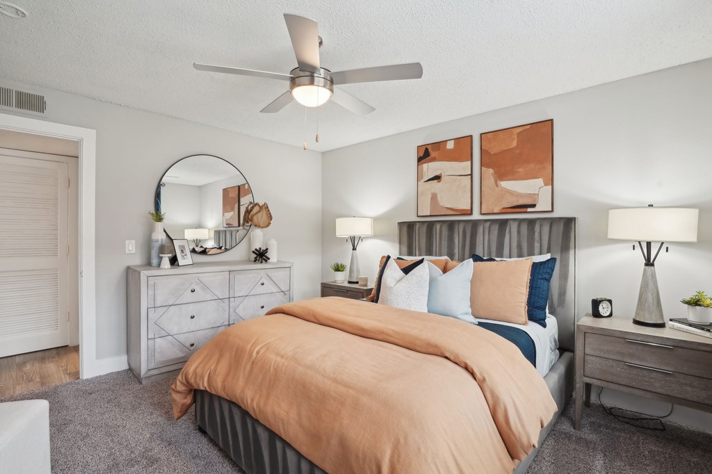 Modern bedroom with gray headboard, orange duvet, and matching abstract art.