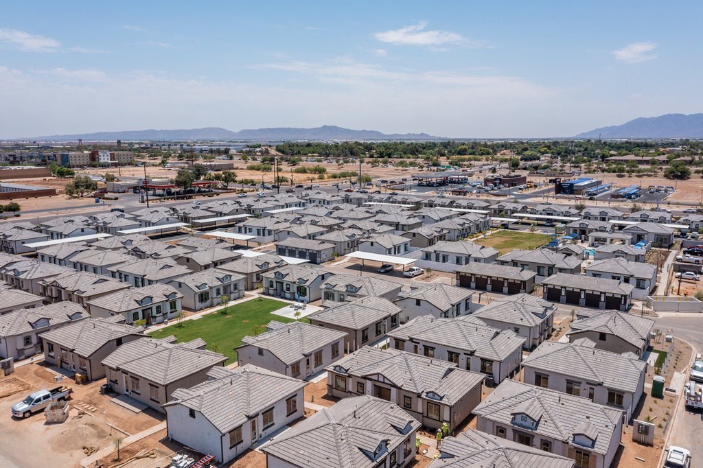 A large housing development with numerous houses and a green space in the middle.