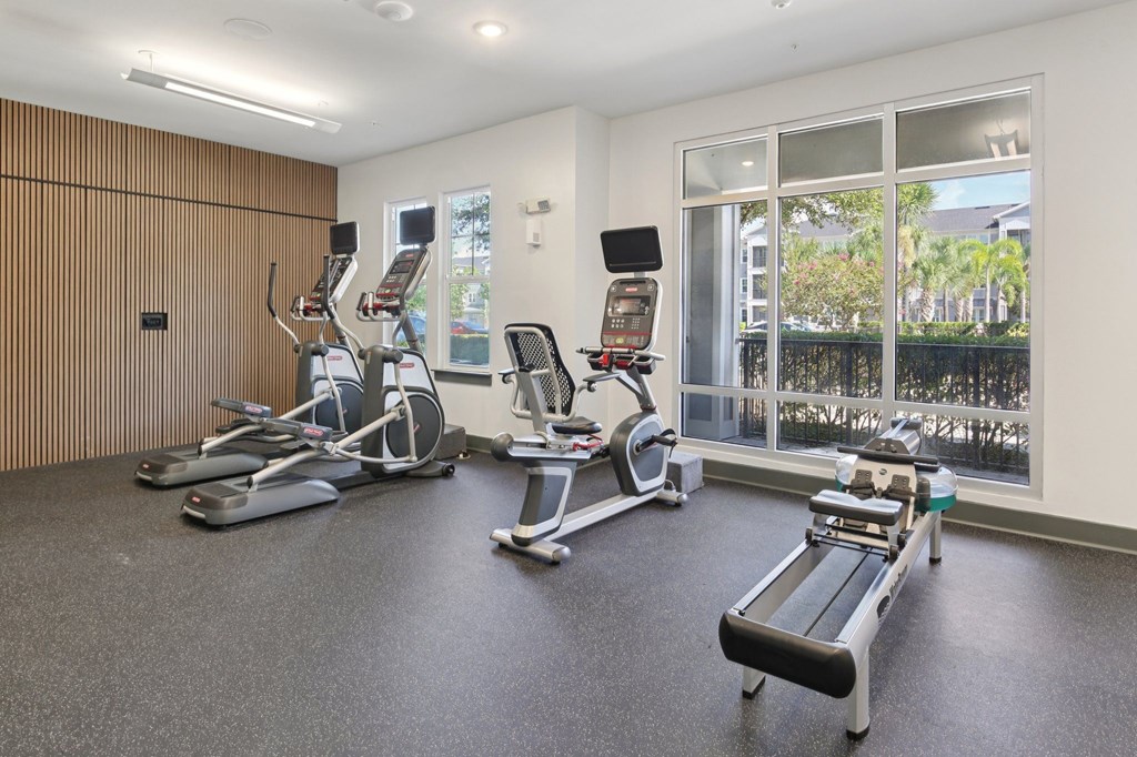 Fitness center with cardio machines and large windows at Lotus at Starkey Ranch in Odessa, Florida.