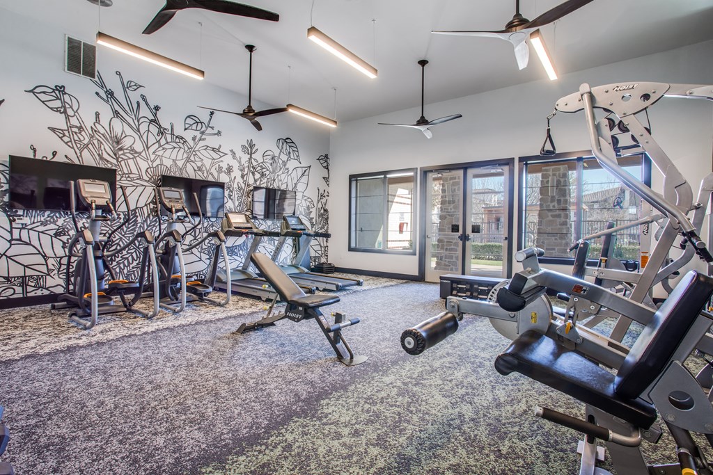 a gym with exercise equipment and a mural on the wall