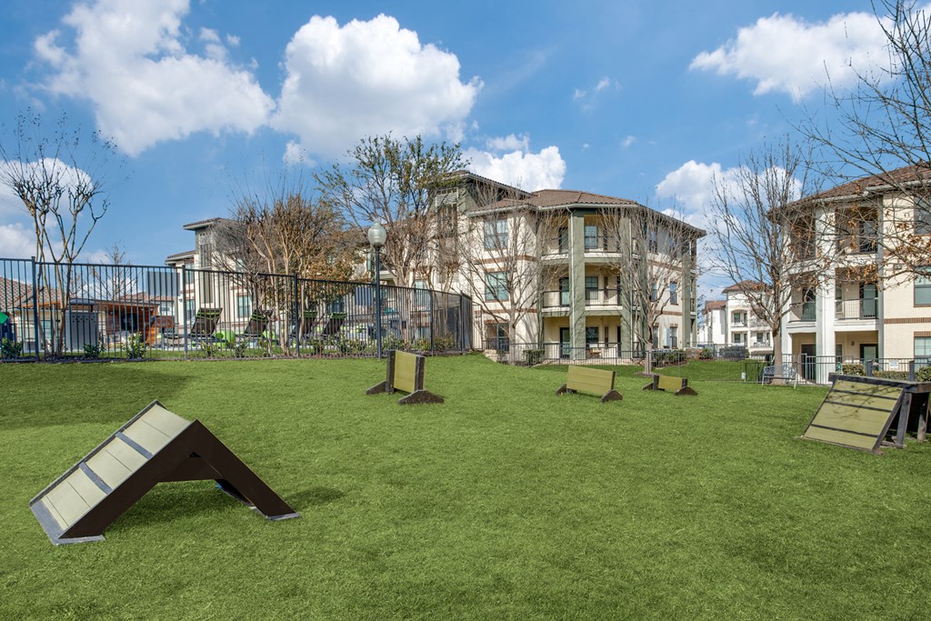a grassy area with benches and buildings in the background