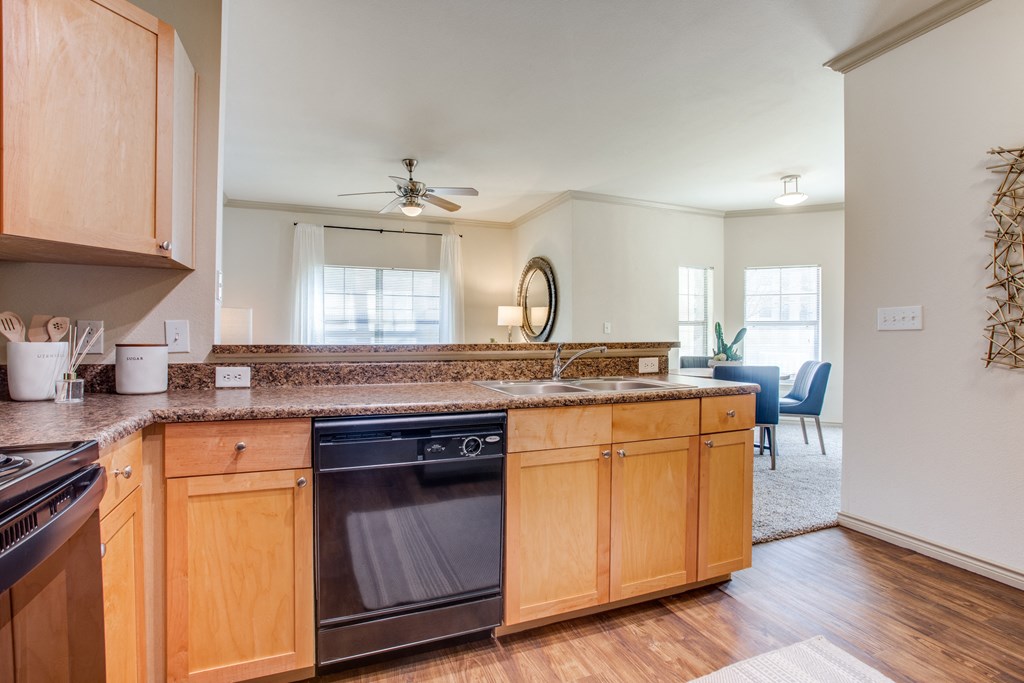 a kitchen with wooden cabinets and a counter top with a dishwasher