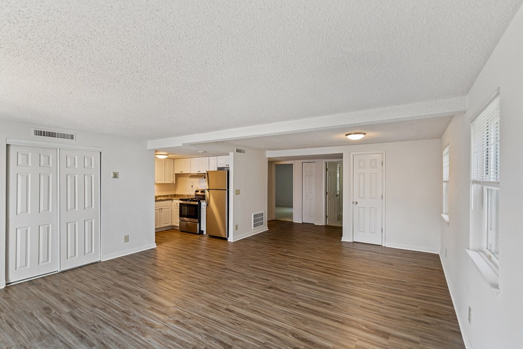 the living room and kitchen of an apartment with wood flooring