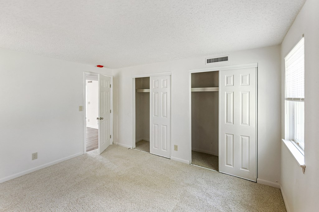 the living room of an empty apartment with three doors