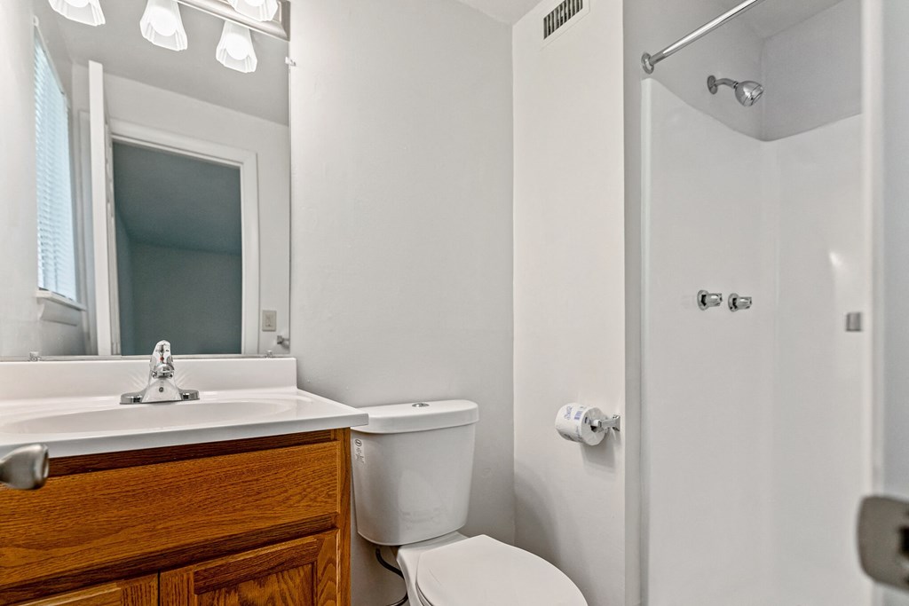 a bathroom with a toilet sink and mirror and a shower