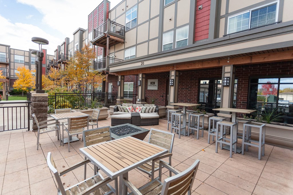 a patio with tables and chairs outside of an apartment building