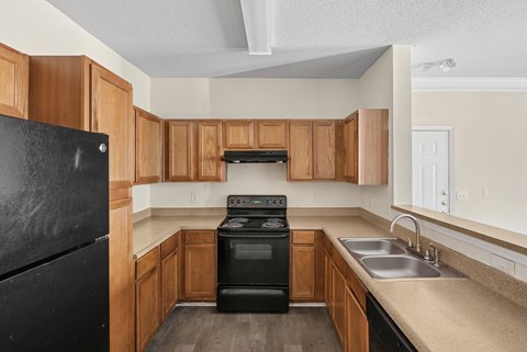 A kitchen with a black refrigerator, black oven, and wooden cabinets.