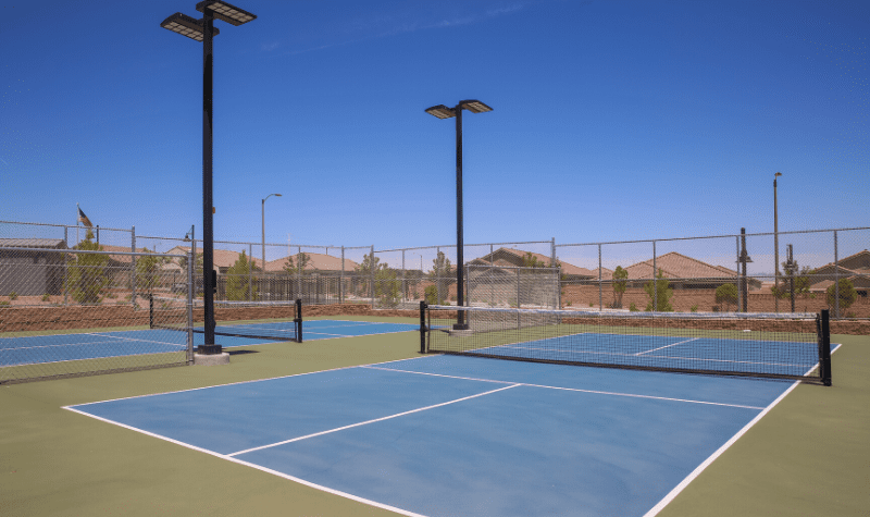two tennis courts with lights on top of a fence