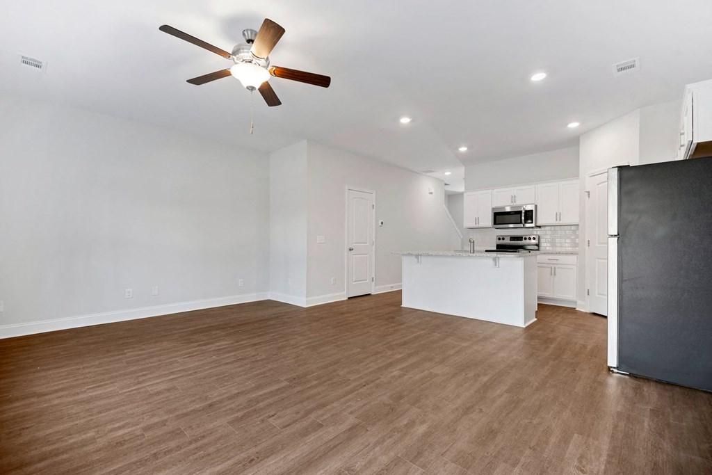 an empty living room and kitchen with a ceiling fan