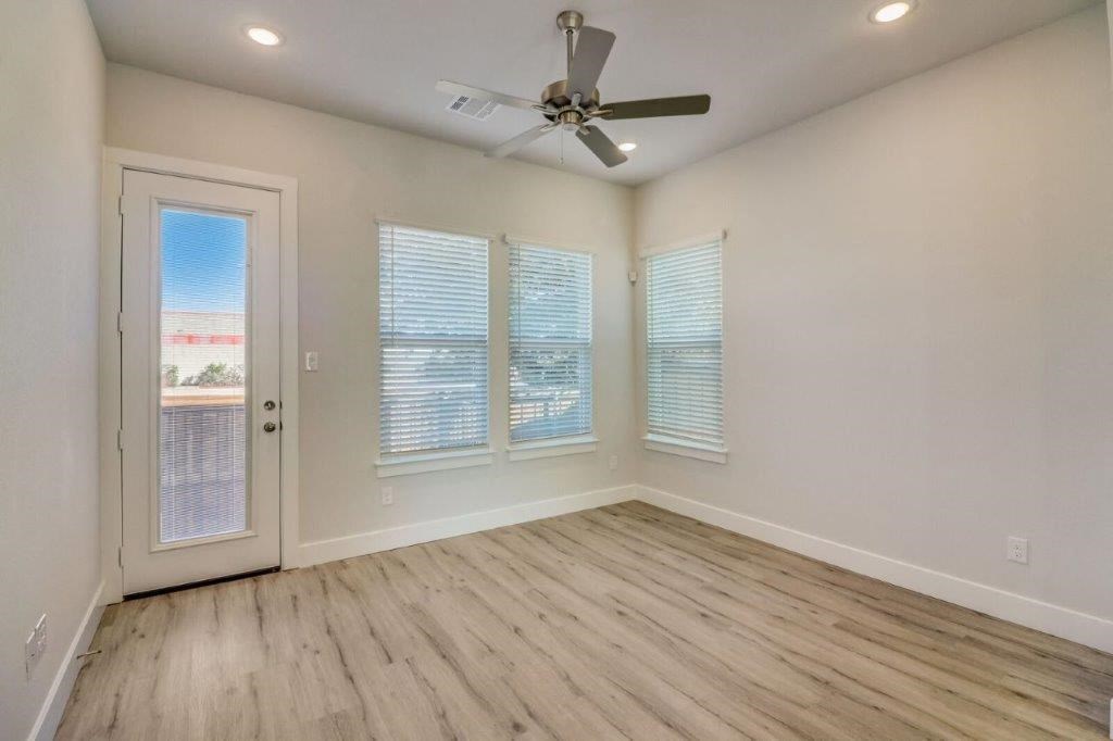 an empty living room with a ceiling fan and a door