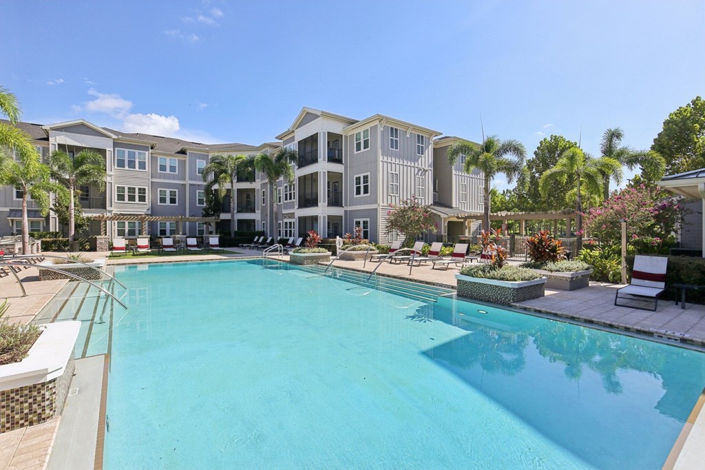 Swimming pool area with adjacent outdoor patio and shaded lounge chairs at Lotus at Starkey Ranch in Odessa, Florida