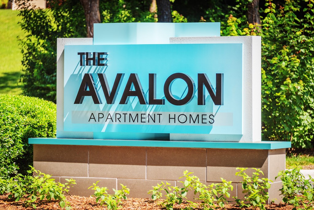 a sign that says the avalon apartment homes in front of trees