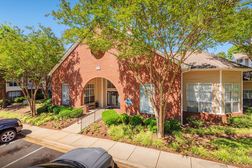 the front of a brick house with trees and a sidewalk