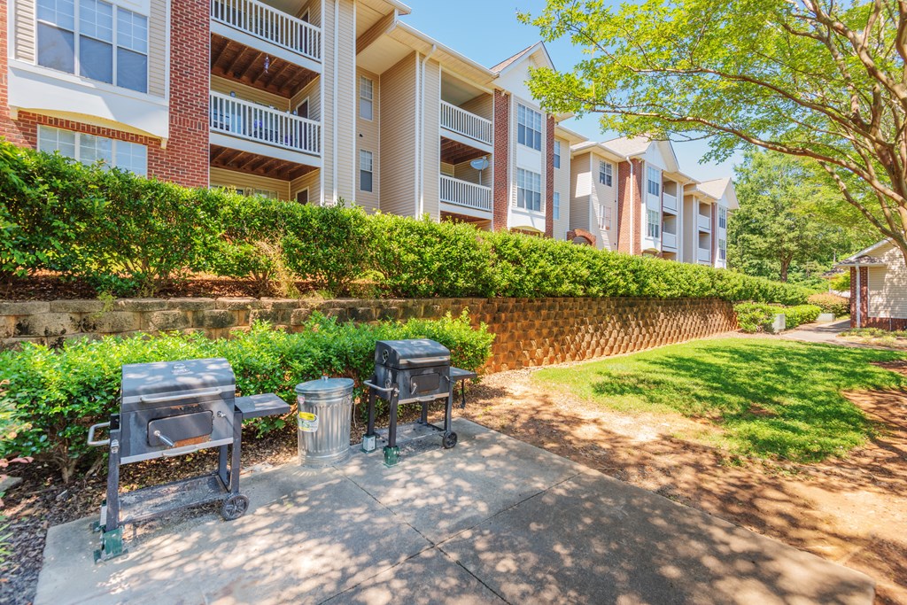 a patio with two barbecue pits in front of an apartment building