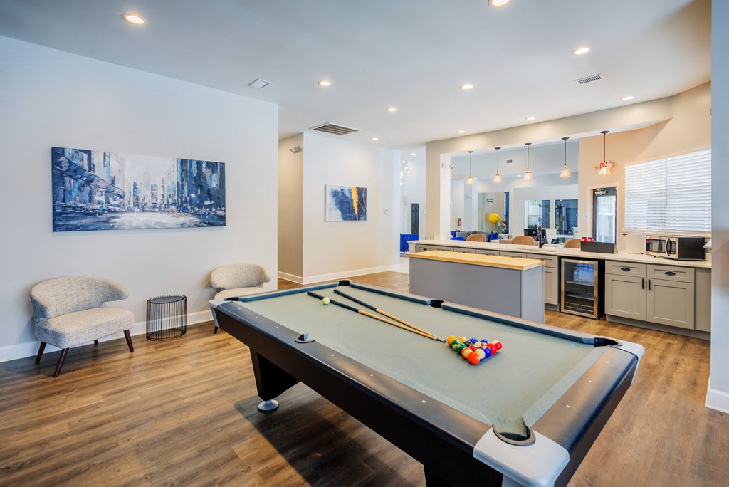 a pool table in a living room with a kitchen