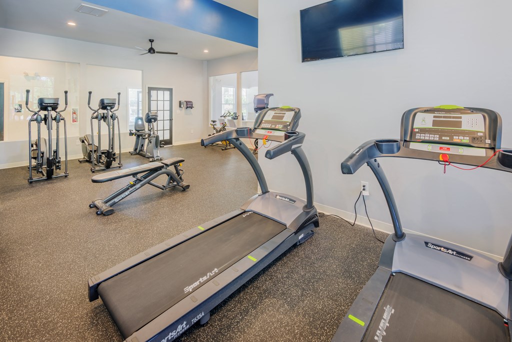 the gym with treadmills and other exercise equipment at the belmont shores apartments