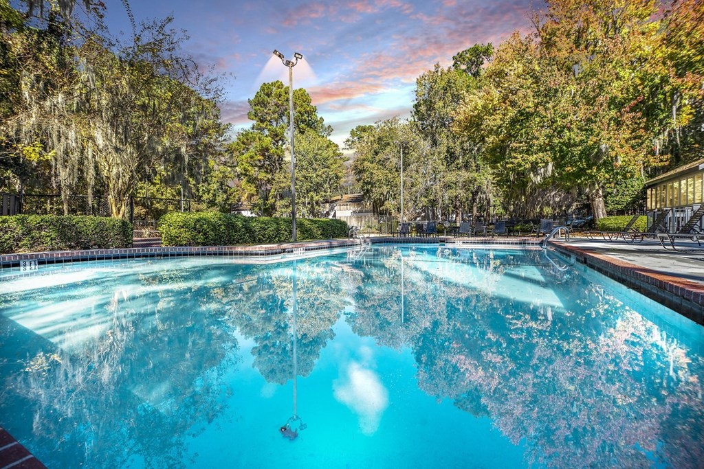 Greentree Apartments in Savannah, GA photo of a swimming pool with trees in the background and a cloudy sky