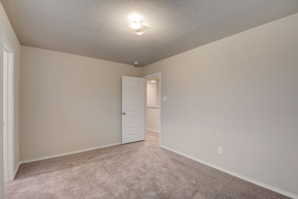 an empty living room with carpet and a door to a closet