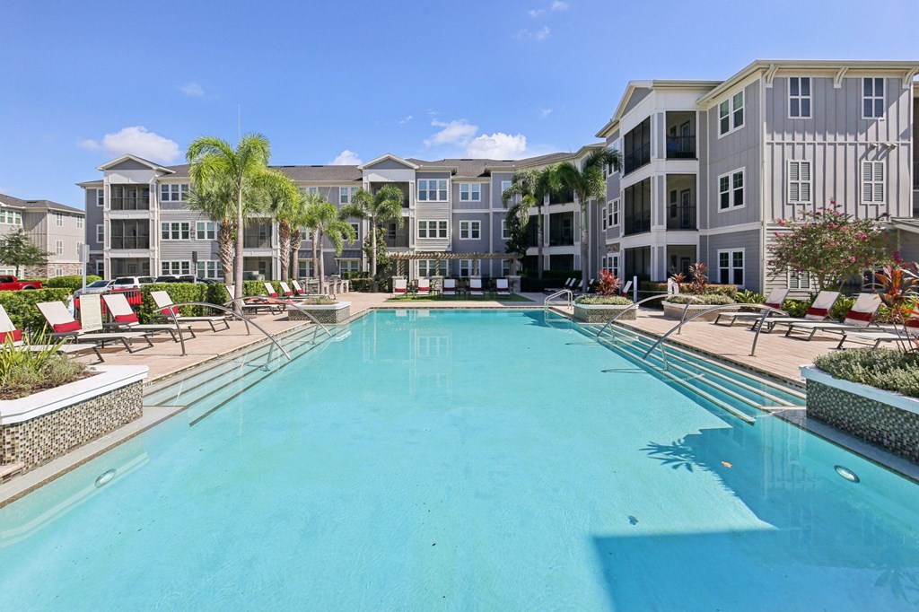 A large swimming pool in front of a building with a red chair.