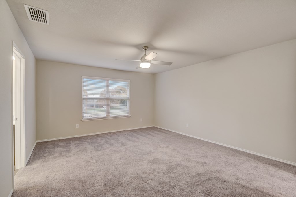an empty living room with a ceiling fan and a window