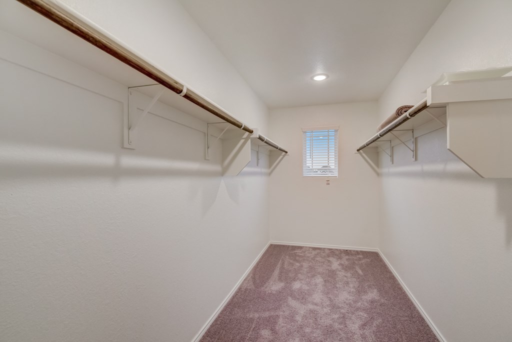 an empty basement with white walls and shelves and a window