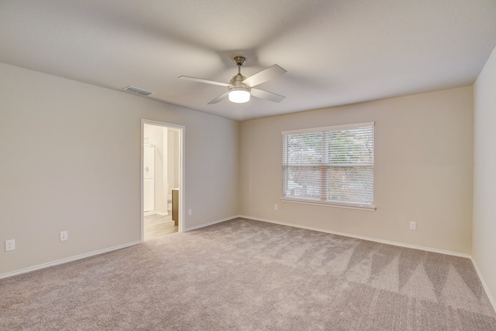 an empty living room with a ceiling fan and a window