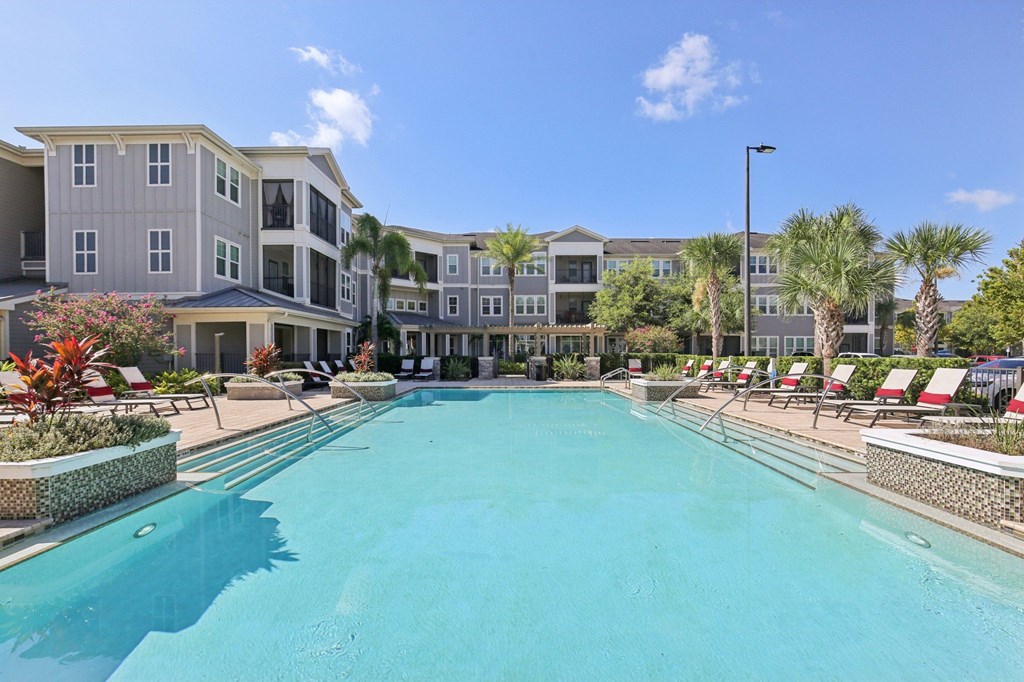 Resort-style swimming pool surrounded by palm trees and landscaped grounds at Lotus at Starkey Ranch in Odessa, Florida.