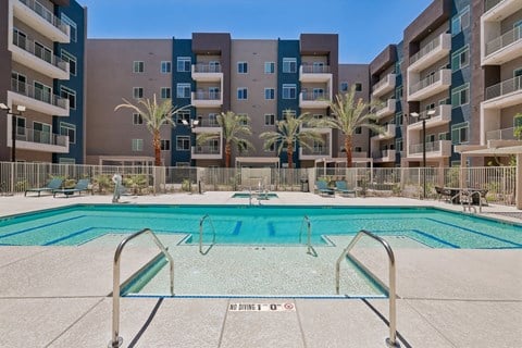 Resort-style swimming pool surrounded by modern apartment buildings at Prosper 150 in Las Vegas