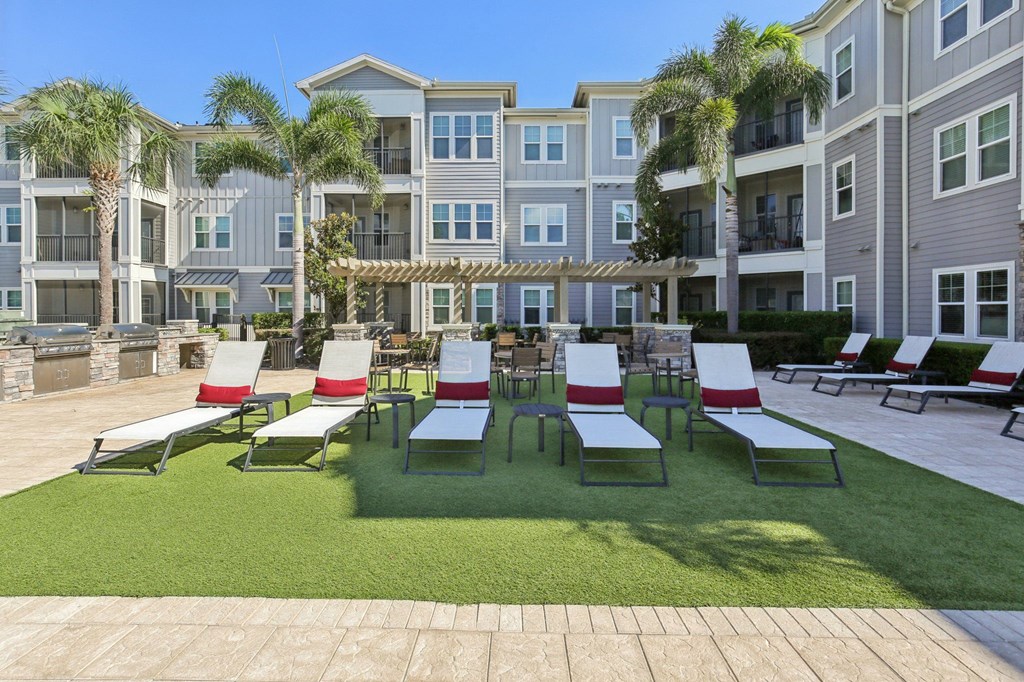 Lounge chairs arranged near palm trees by the pool at Lotus at Starkey Ranch in Odessa, Florida.