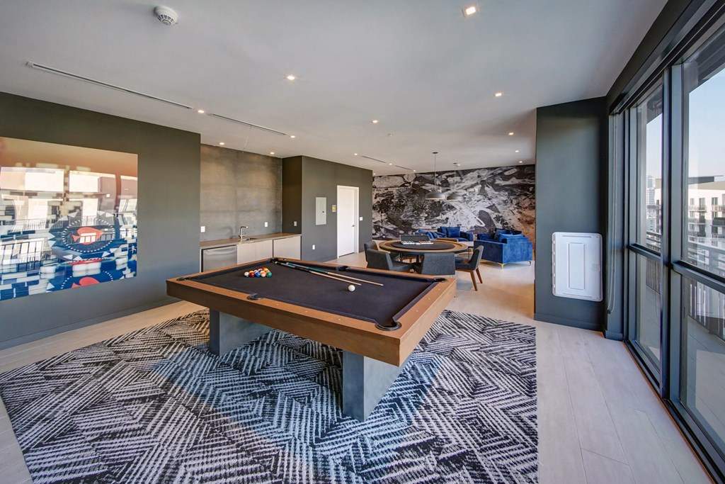 a billiards table in a living room with glass doors and a rug