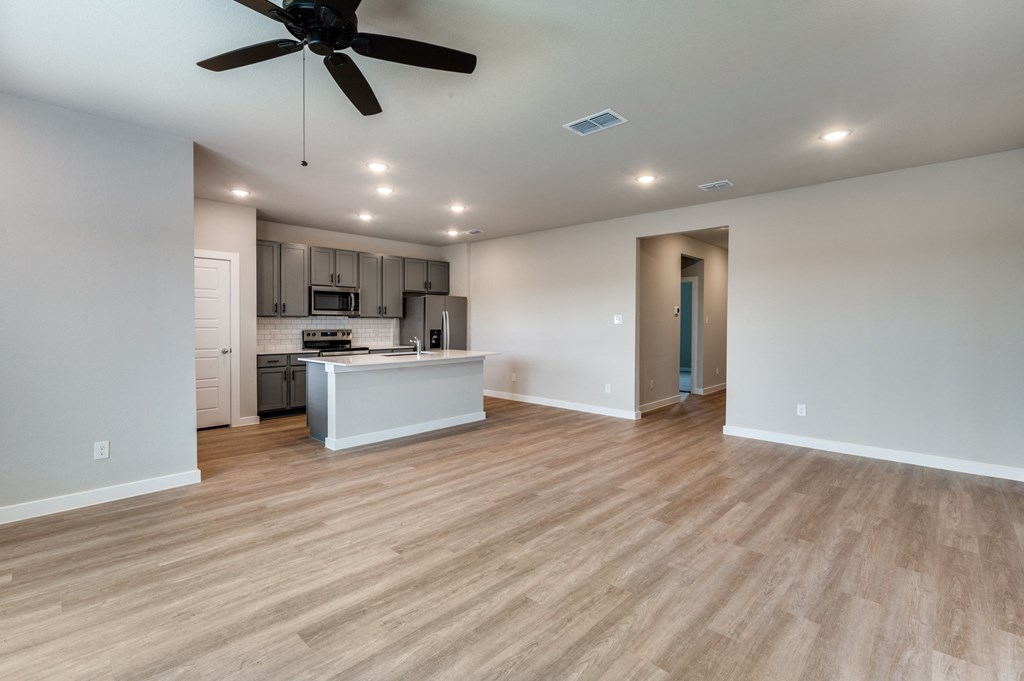 a living room with a kitchen and a ceiling fan