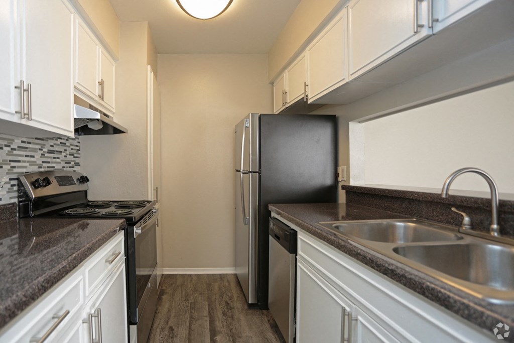 a kitchen with granite counter tops and a stainless steel refrigerator