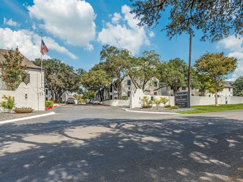 A sunny day at the entrance of a residential area with a flag flying in the background.