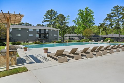Apartment complex swimming pool with lounge chairs and grill.