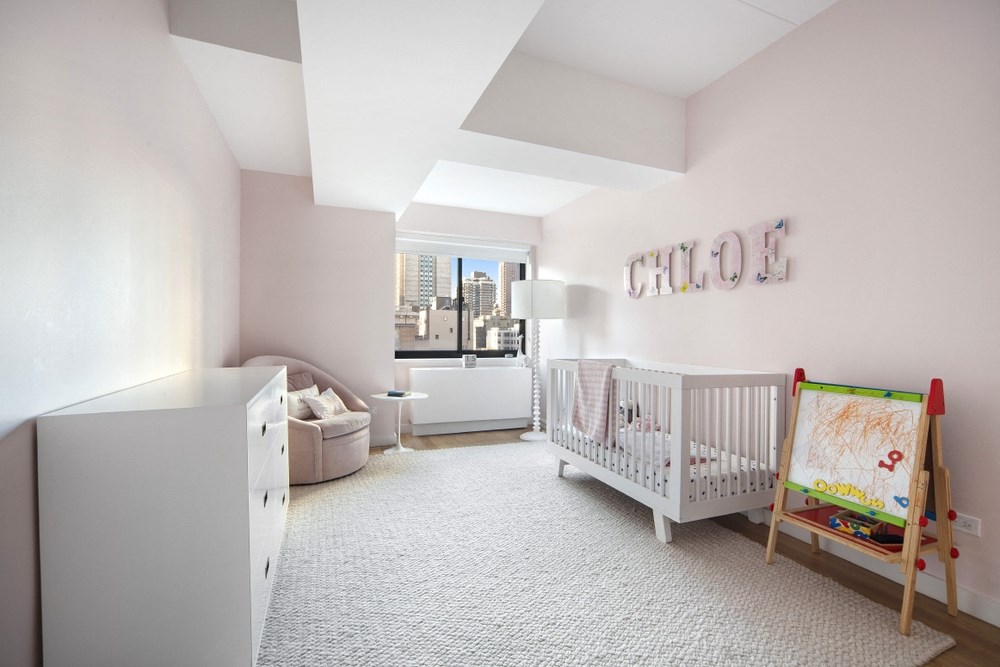 a baby nursery with a crib and a dresser and a window