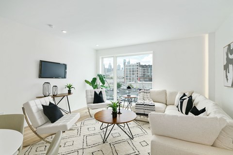 A living room with white furniture and a flat screen TV mounted on the wall.