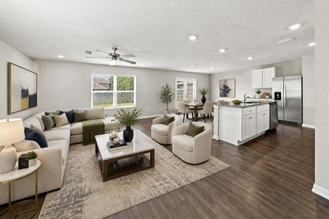 A modern living room with a white sofa set, a coffee table, and a kitchen area in the background.