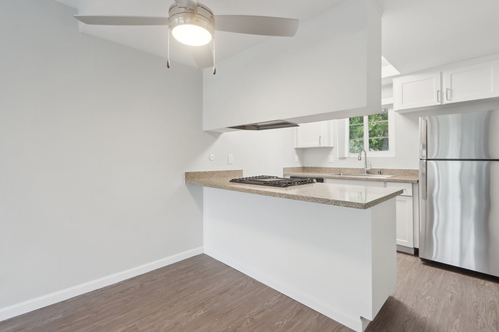 A modern kitchen with a white countertop and a ceiling fan.